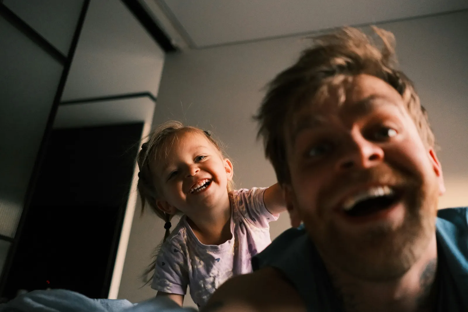 A dad and his little daughter laughing at the camera